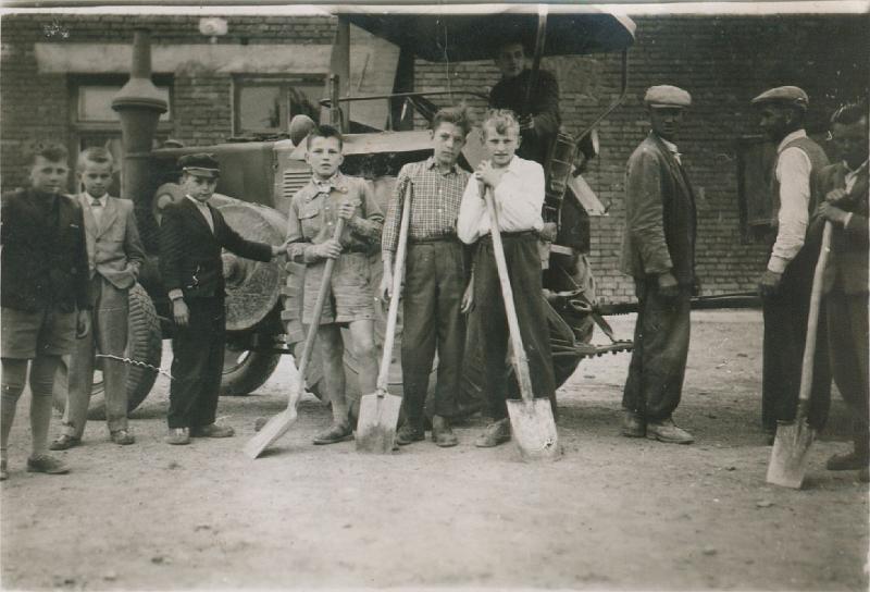 1958-4.jpg - Udział dzieci w pracach obok budynku szkoły. Na traktorze Edmund  Sypień, a trzeci z prawej Józef Chomentowski.  Zdjęcie z roku 1958